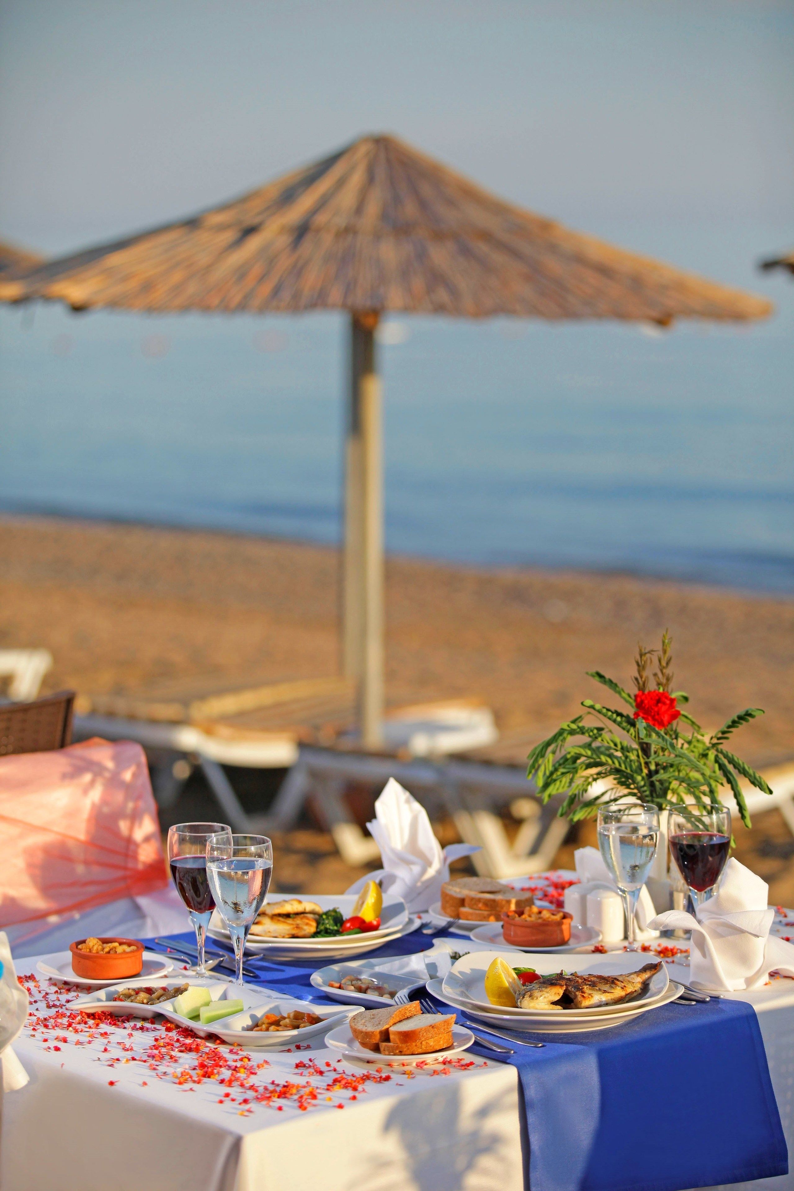 A table set for a meal with a view of the beach and ocean in the background.