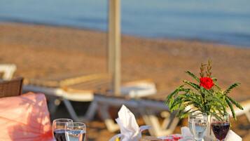 A table set for a meal with a view of the beach and ocean in the background.