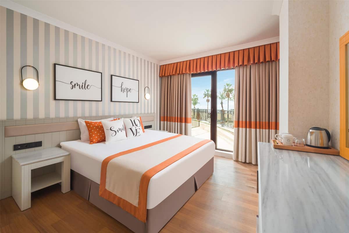 A hotel room with a large bed, a bedside table, a desk, and a view of the outdoors.