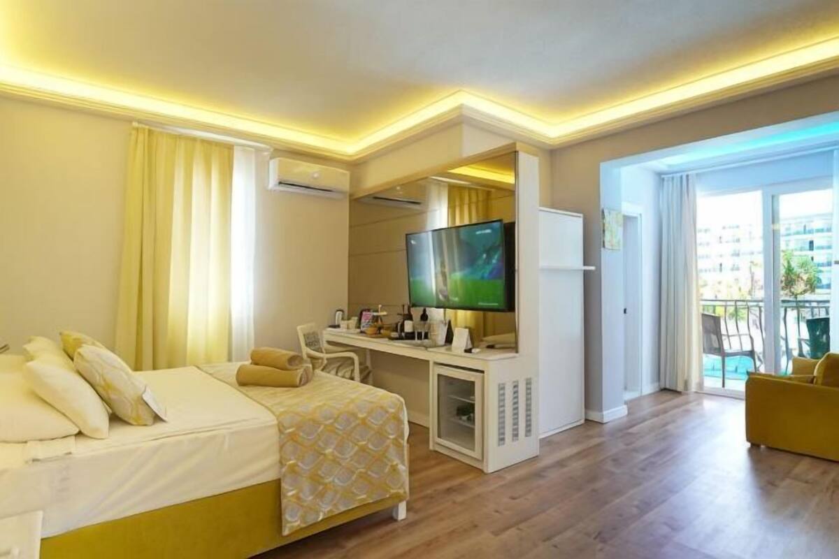 A hotel room with a bed, desk, TV, and a balcony with a view.