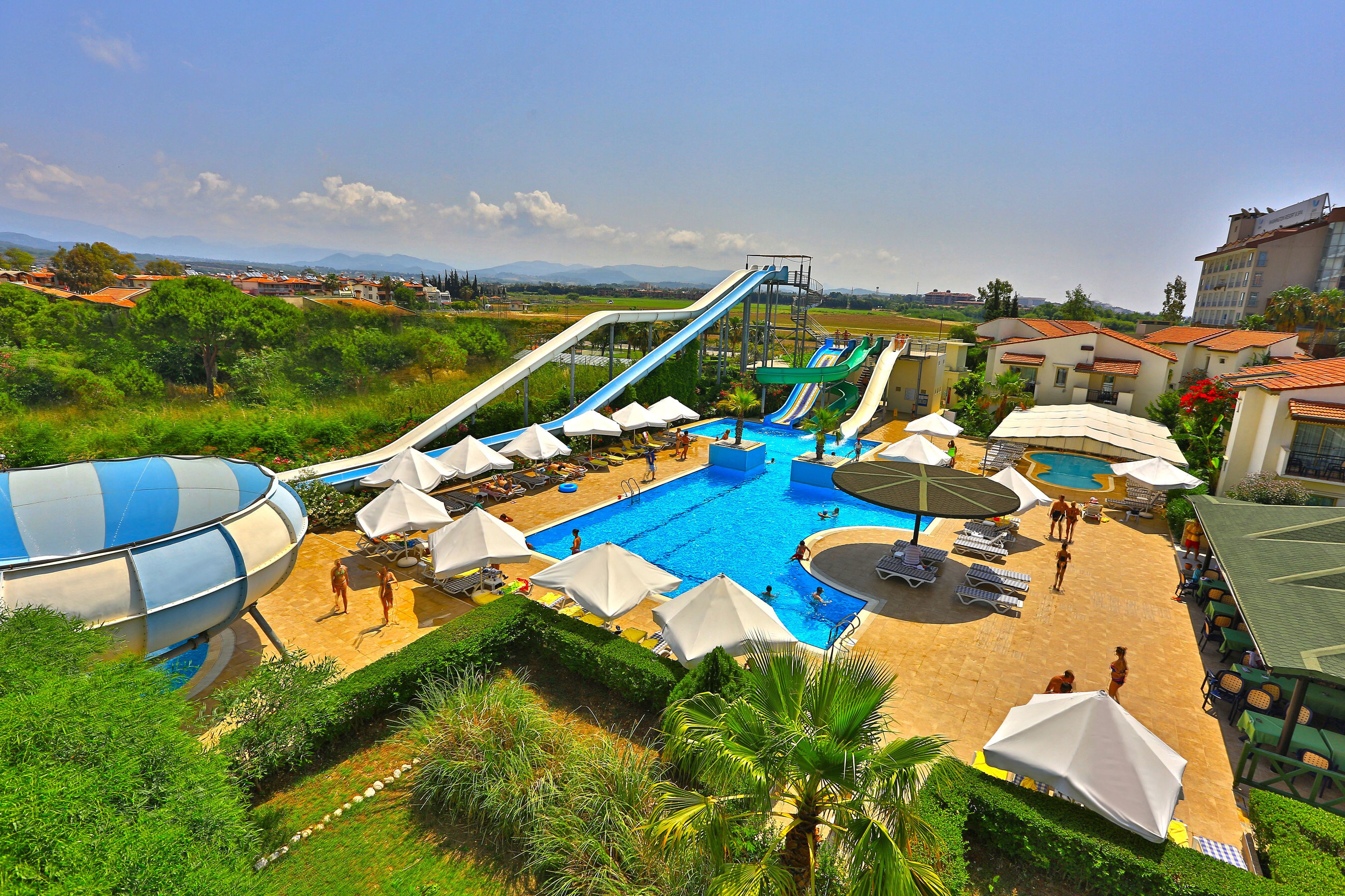 A resort with a large swimming pool, multiple water slides, and sun loungers.