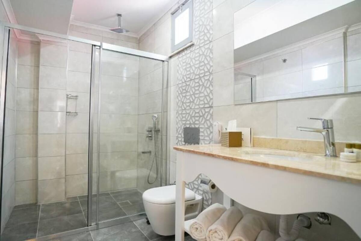 A modern bathroom with a glass-enclosed shower, a toilet, and a vanity with a mirror.