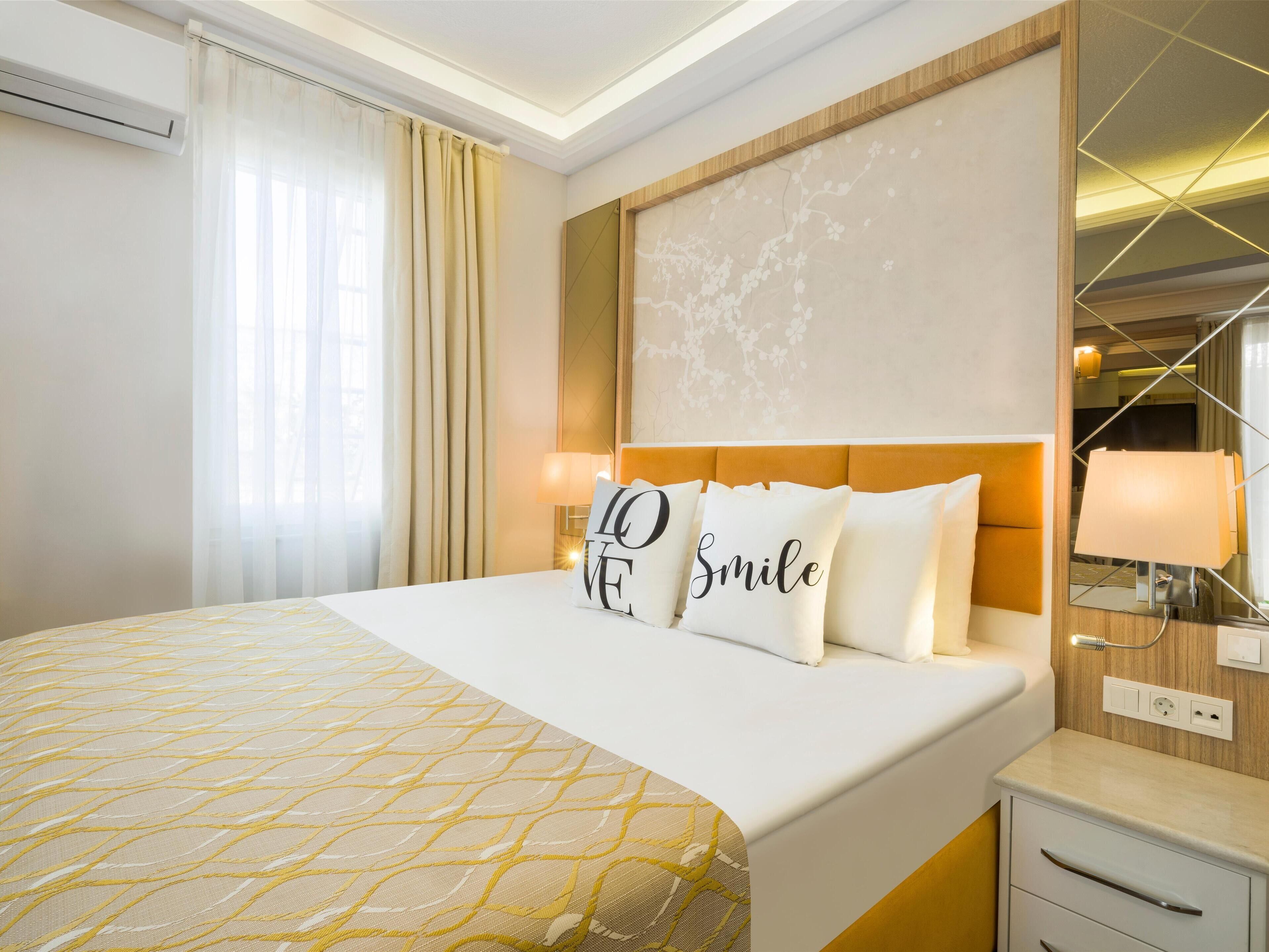 Habitación de hotel con una cama grande, una mesita de noche, un espejo y una pared con estampado floral.