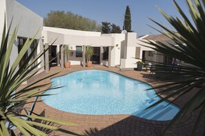 Una piscina al aire libre, sillones reclinables de piscina