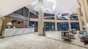 Eine geräumige Lobby mit einer Marmor-Rezeption, einer Sitzecke und einer großen dekorativen Lichtinstallation.