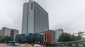 Ein hohes, modernes Hotelgebäude mit Glasfassade und einer markanten Eingangshalle.