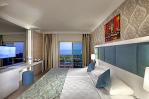 Une chambre d’hôtel avec un grand lit, un bureau avec une télévision, un balcon avec vue et un élément décoratif mural.