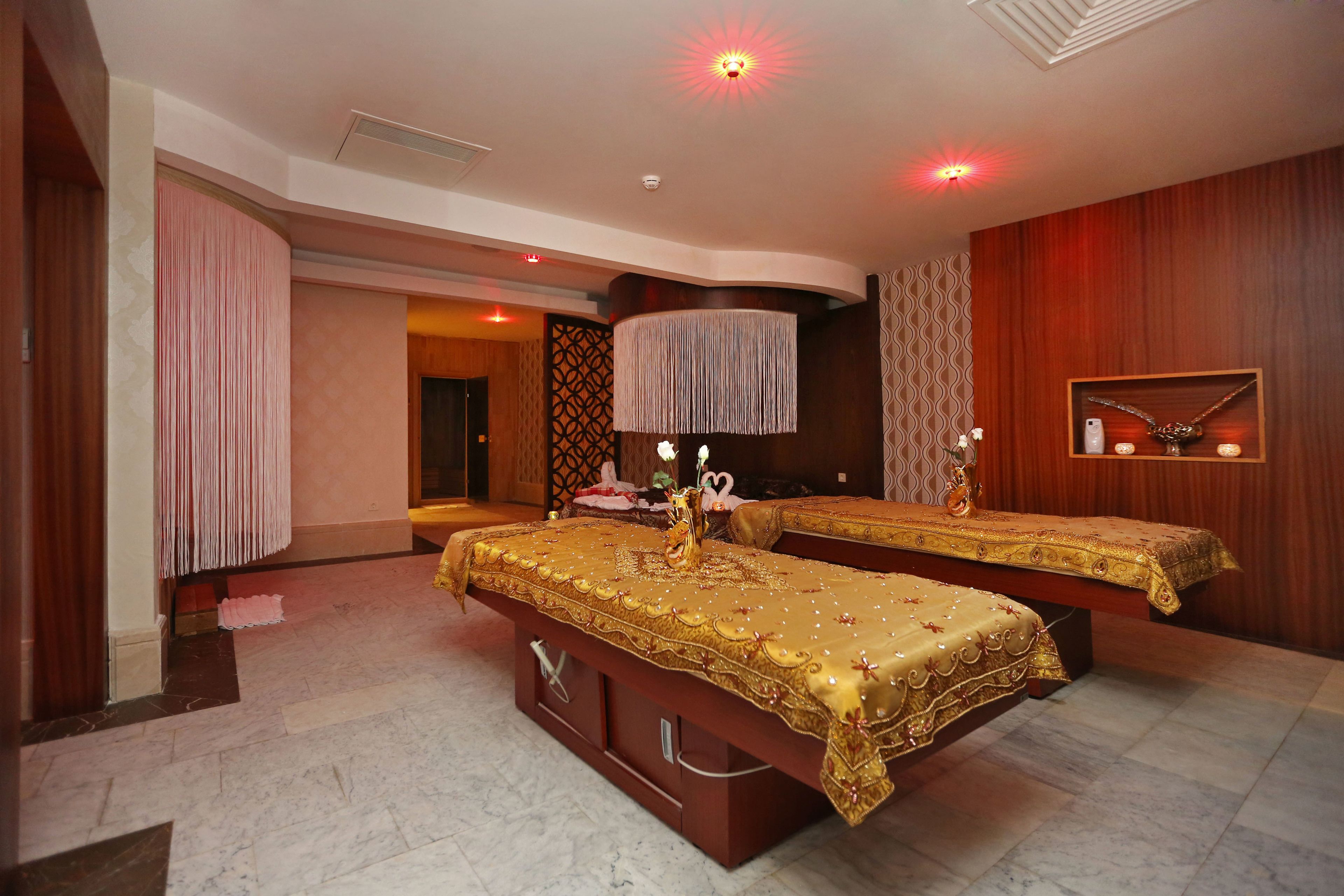 A hotel room with two beds, a large mirror, and a chandelier.