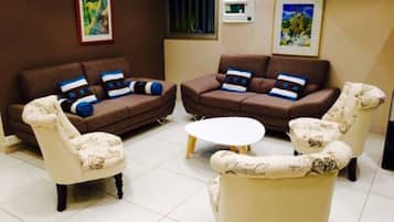 A living room with two brown sofas, two patterned armchairs, and a round coffee table.