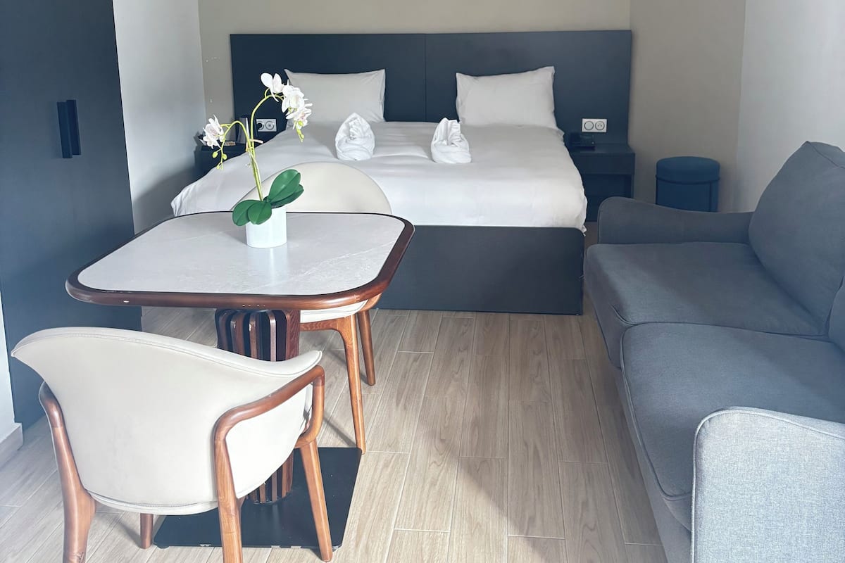 Una habitación de hotel moderna con una cama, una mesa de comedor con sillas y un sofá.