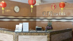 Bancada de recepção de hotel com relógio, lanternas vermelhas e uma placa com a inscrição "012 HOTEL".