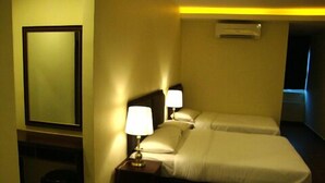 Quarto de hotel com cama, duas luminárias de cabeceira, um espelho e um aparelho de ar condicionado.