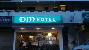 Um edifício de vários andares com uma placa chamativa que diz "DM HOTEL" no andar térreo.