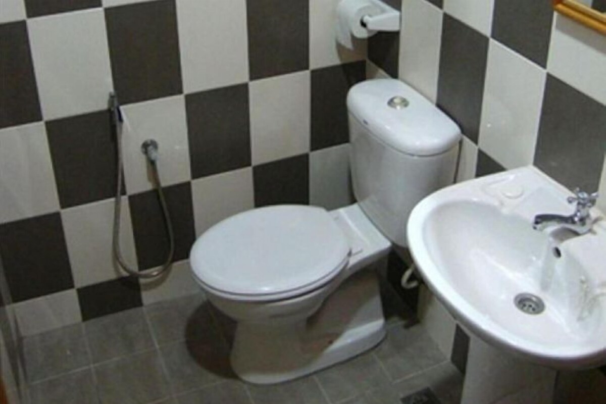 A bathroom with a toilet, sink, and a checkered wall pattern.