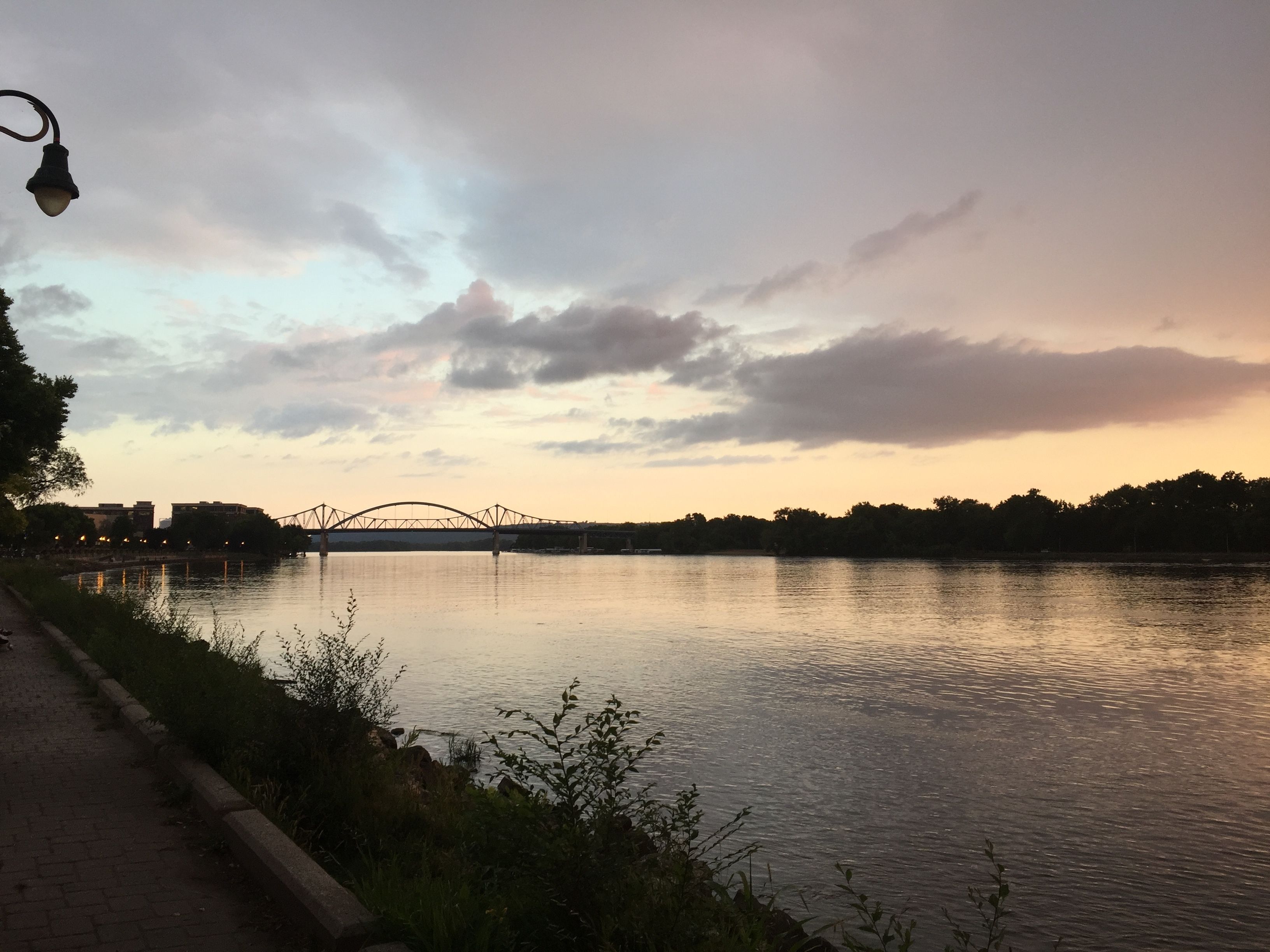 Ein Fluss mit einer Brücke, einem Gehweg und einem Laternenpfahl.