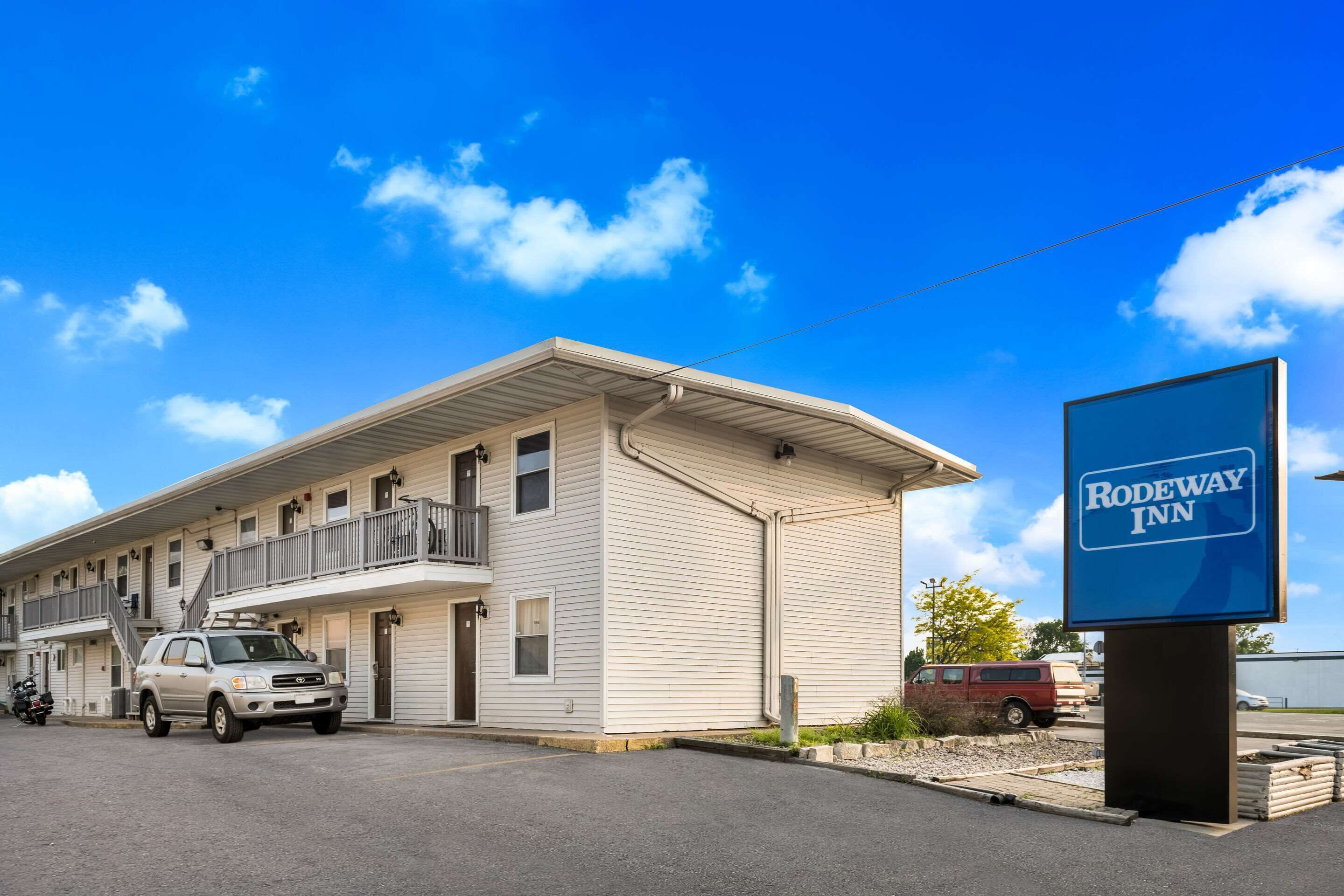 A motel with a two-story structure, a covered parking area, and a signboard.