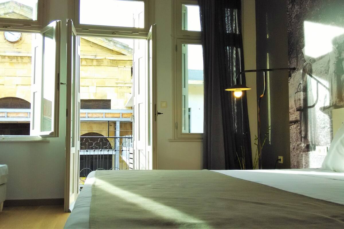Et hotelværelse med en seng, et vindue og udsigt til en bygning.