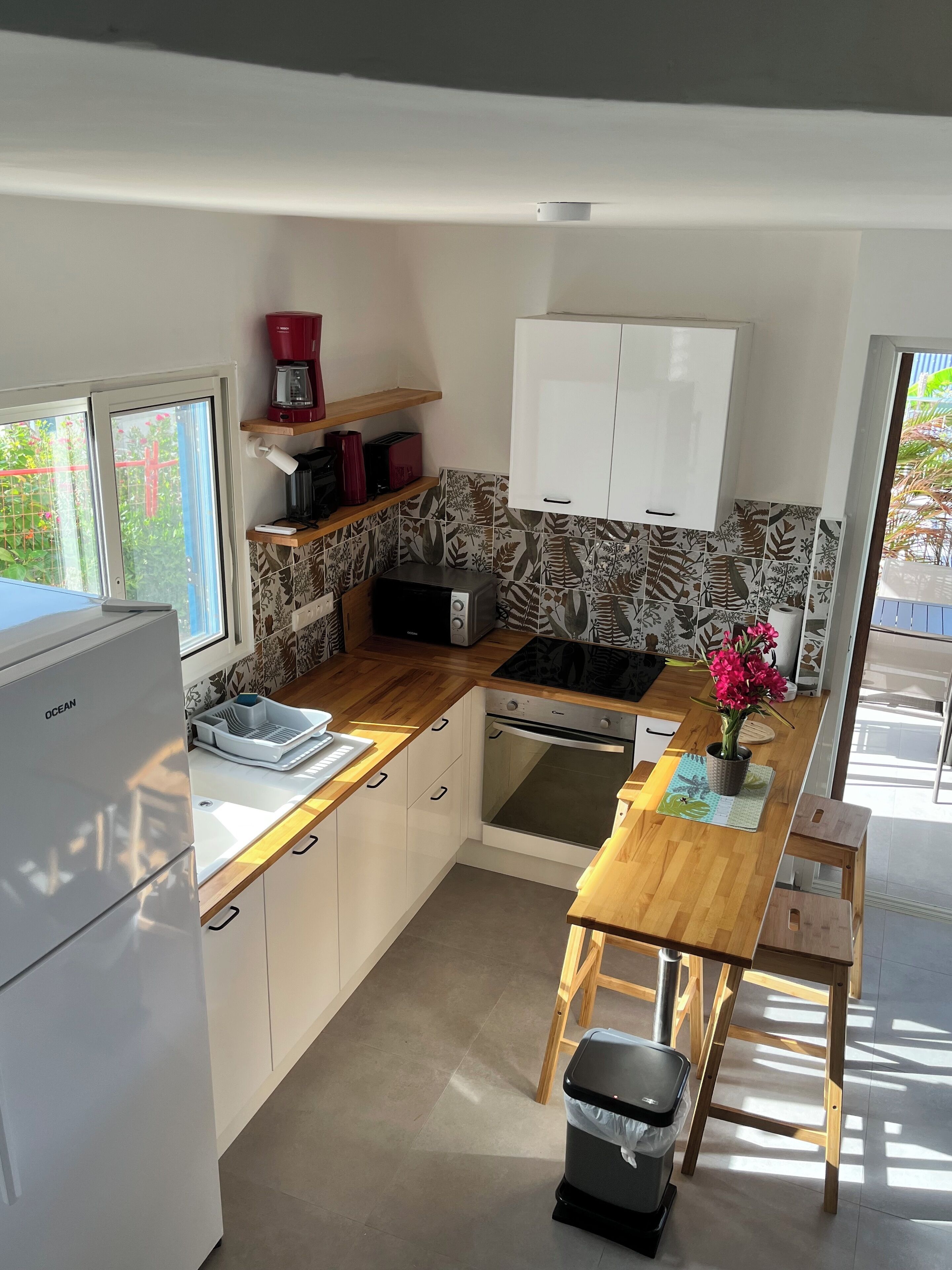 A compact kitchen with a refrigerator, microwave, oven, and wooden countertop.