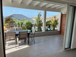 Un balcon avec une table et des chaises, donnant sur une piscine et un espace verdoyant.