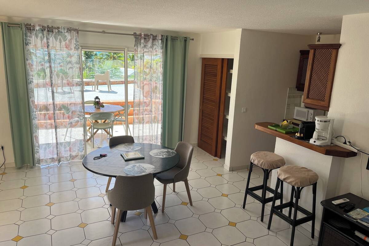 A dining area with a round table, two chairs, a coffee machine, and a microwave on a countertop.