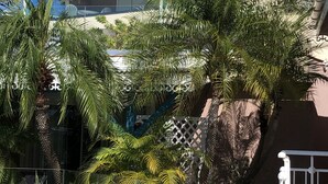 A hotel with a covered outdoor area, palm trees, and a staircase leading to an upper level. - Colombus Résidence (Oyster Pond)