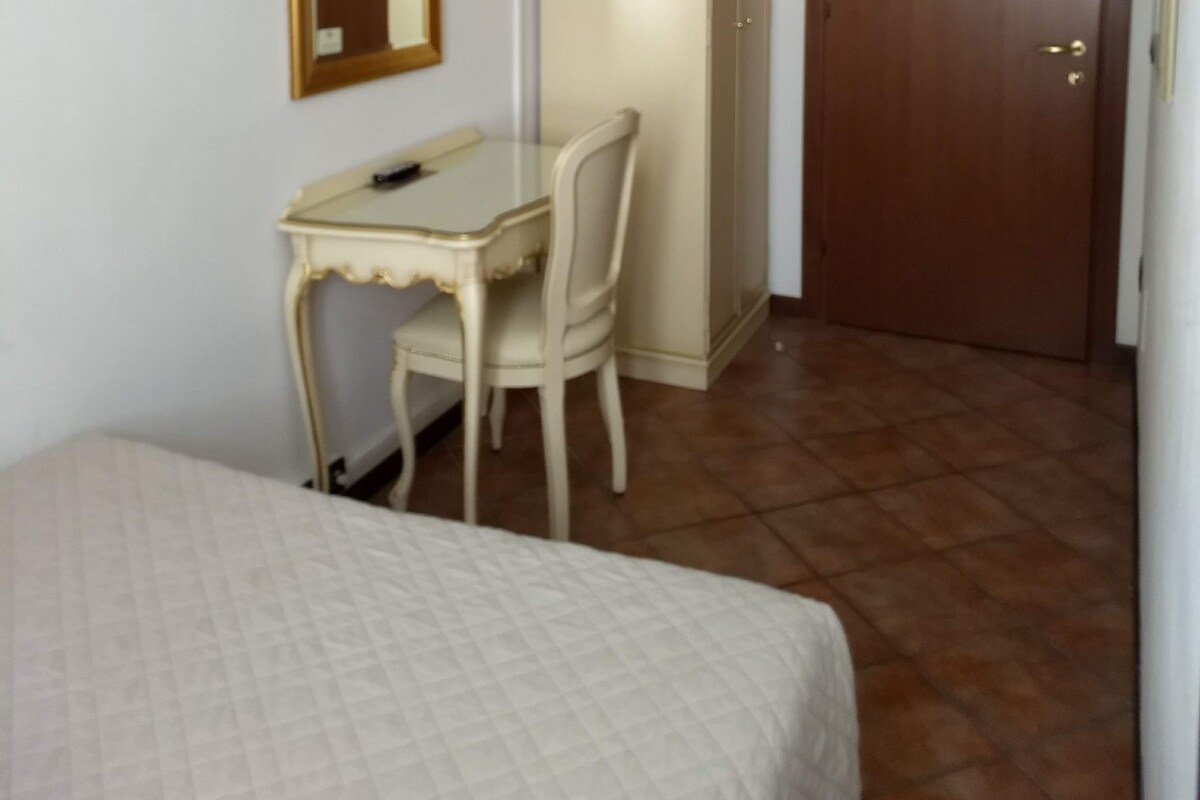 A bedroom with a bed, a desk, a chair, a television, and a wardrobe.
