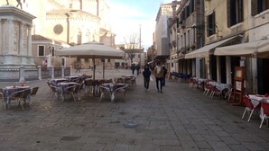 Una calle adoquinada con mesas al aire libre y un edificio histórico al fondo.
