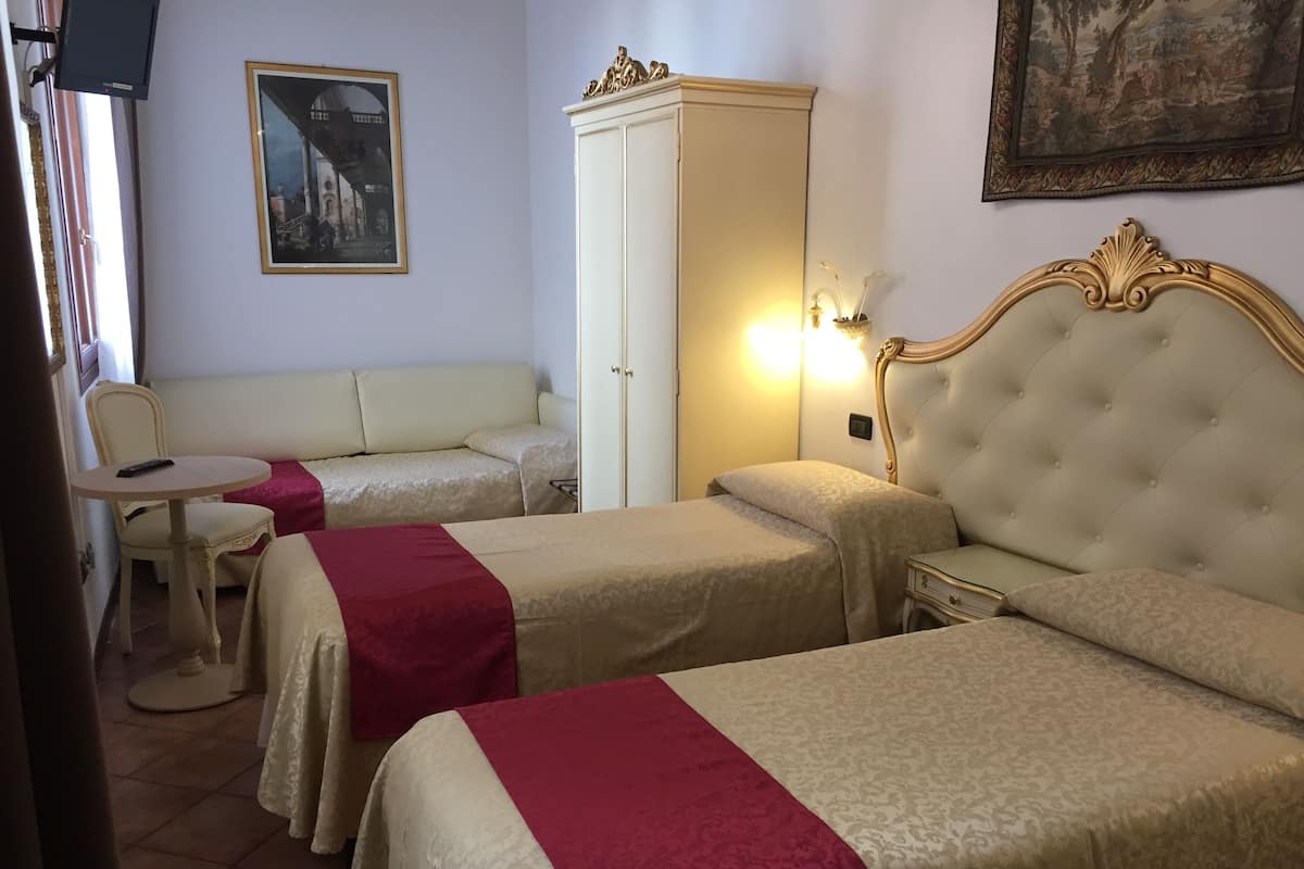 A hotel room with two beds, a sofa, a table, and a wardrobe.