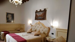 Una habitación de hotel con una cama grande, dos mesitas de noche, una araña y un cuadro en la pared.