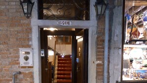 Entrada de un hotel con fachada de ladrillo, puerta de madera y una escalera que conduce al interior.