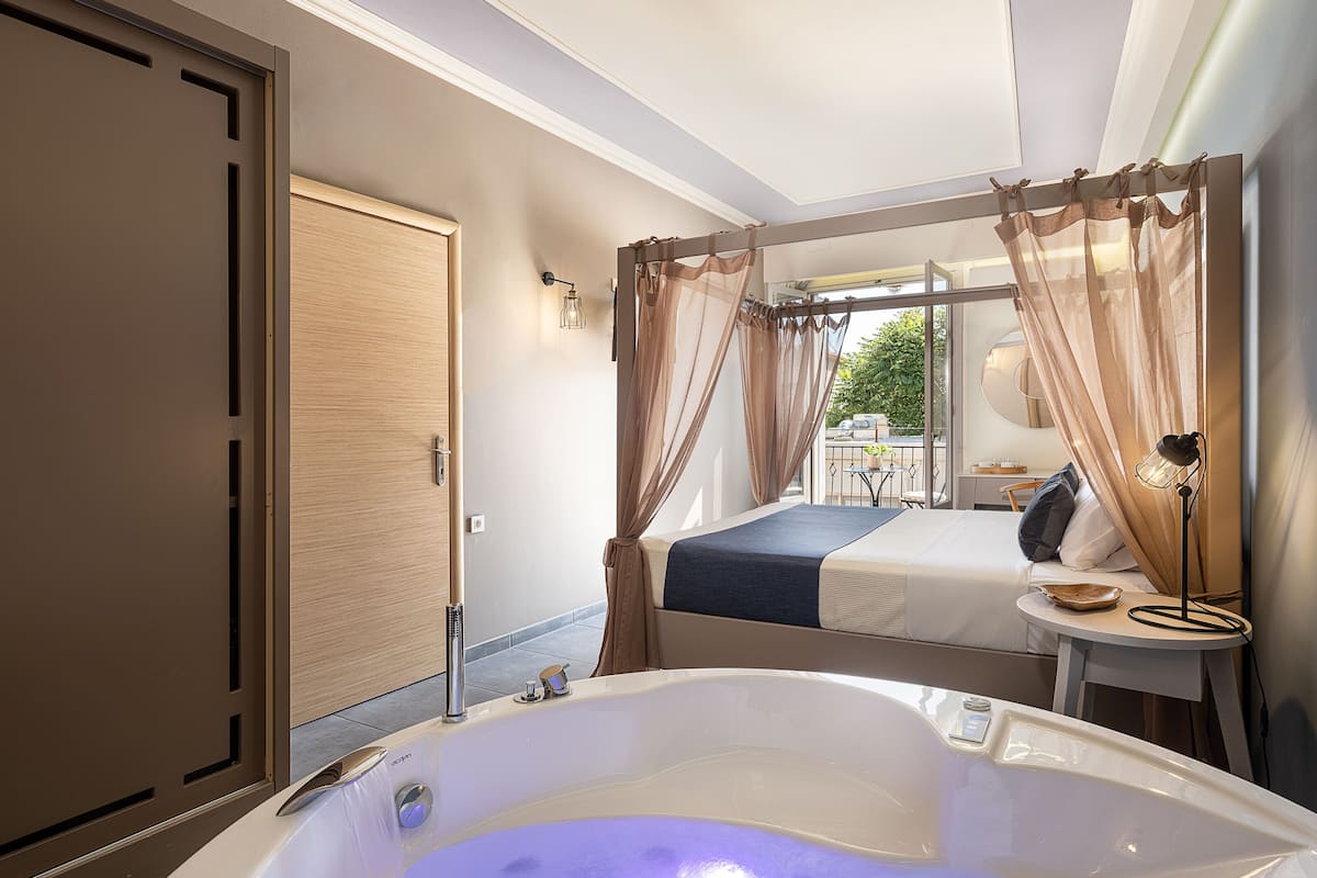 A modern bedroom with a large bathtub, a bed, and a balcony view.