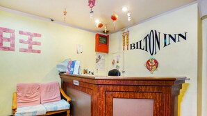Et receptionsområde med en træreception, en sofa og en væg med navnet "BILTON INN".