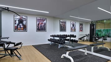 Un gimnasio moderno con equipo de levantamiento de pesas, bancos y mancuernas.