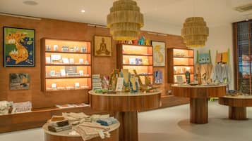 Un hall de hotel boutique bien iluminado, con mobiliario de madera, detalles decorativos en la pared y una variedad de objetos expuestos, incluyendo textiles y joyería.