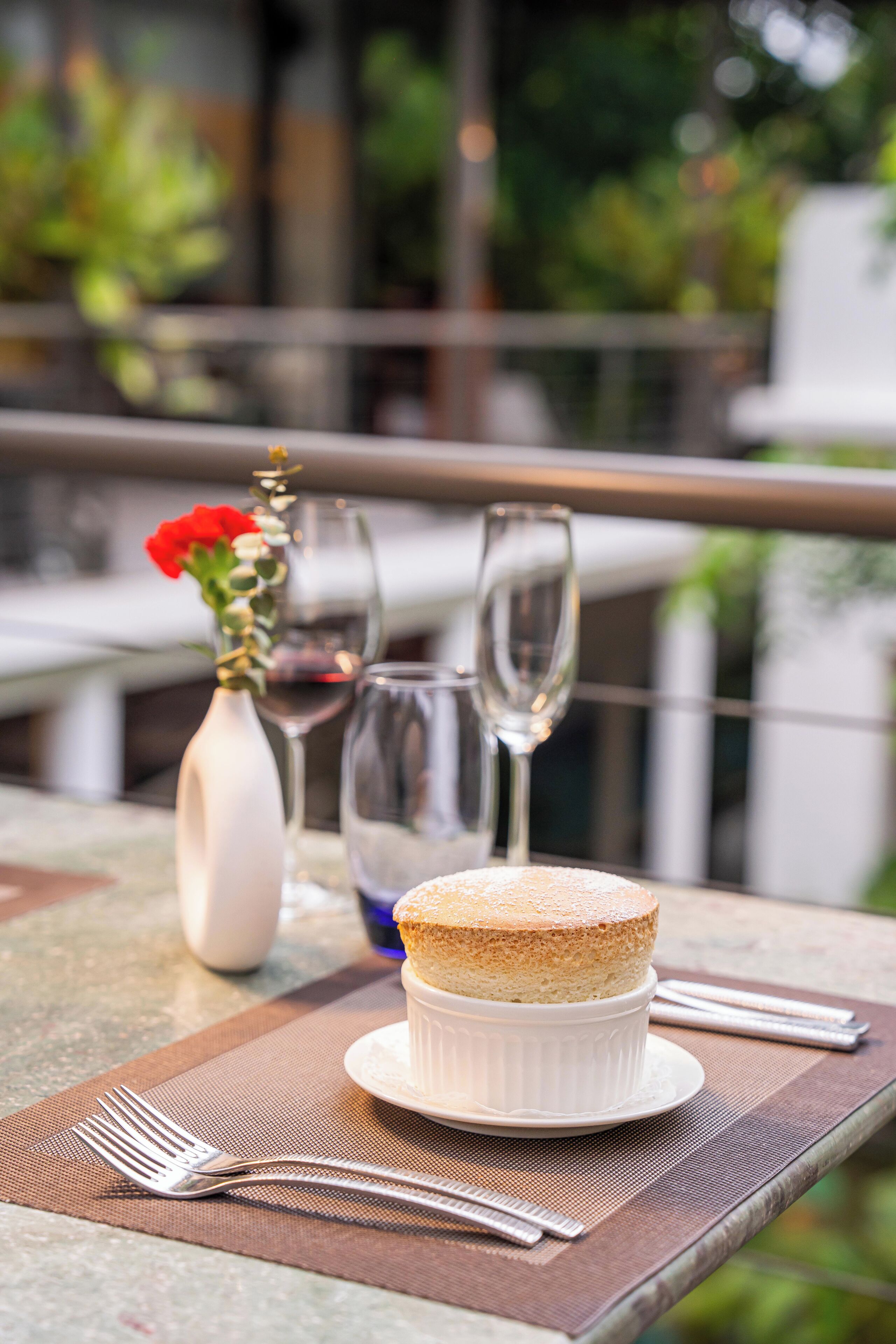Een dessert op een wit bord op een tafel, met een vork en een wijnglas.