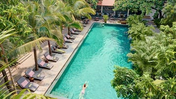 Relax by the serene pool surrounded by lush vegetation and palm trees.