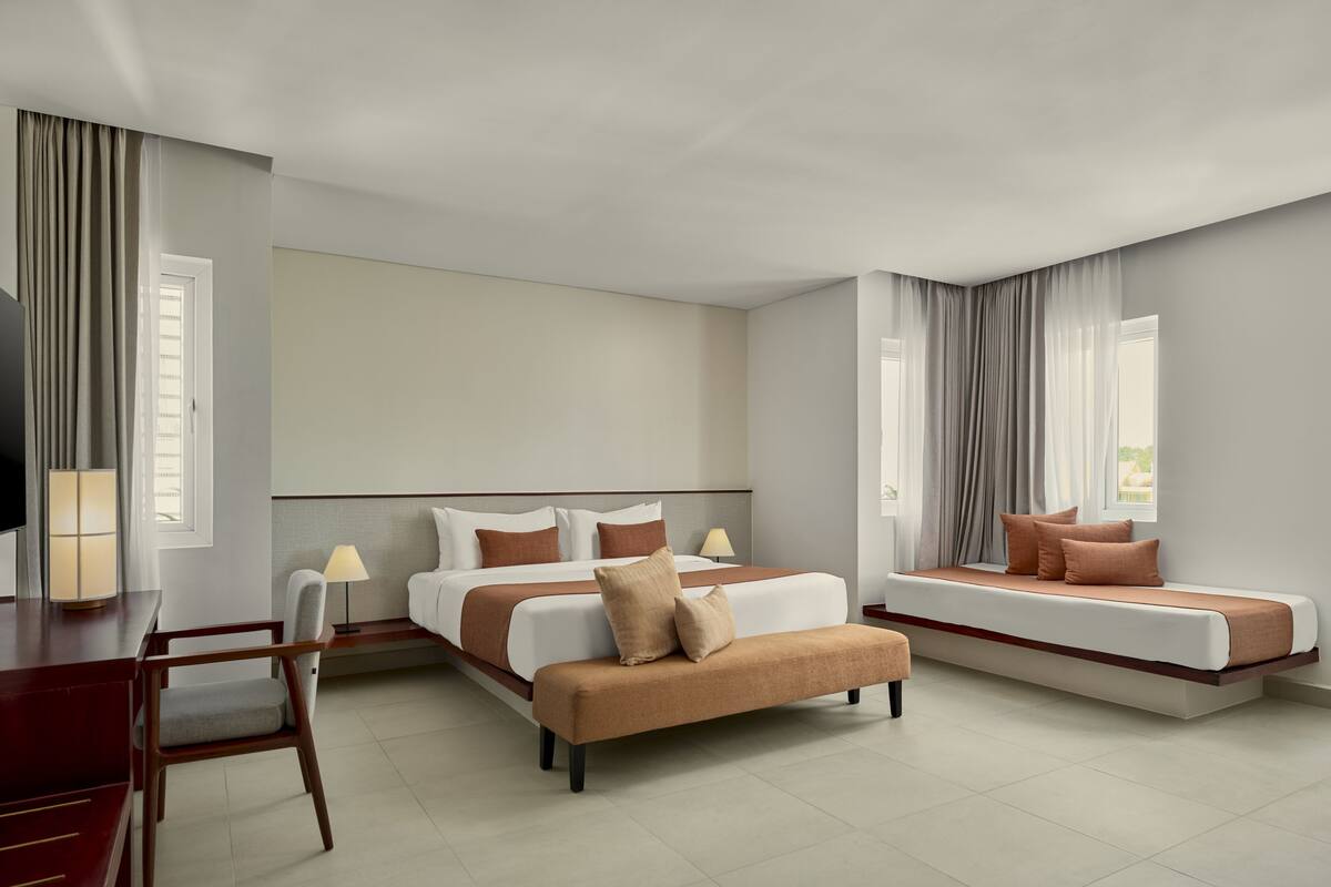 Ein Hotelzimmer mit einem großen Bett, einer Schlafcouch, einem Schreibtisch und einem Stuhl.