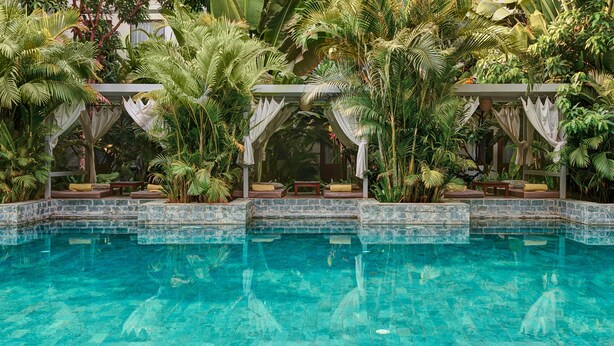 A pool surrounded by lush tropical plants and a stone-tiled edge. - Plantation Urban Resort & Spa (Phnom Penh)