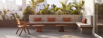 Un espacio exterior moderno con sofás, dos mesas redondas y una silla de madera.