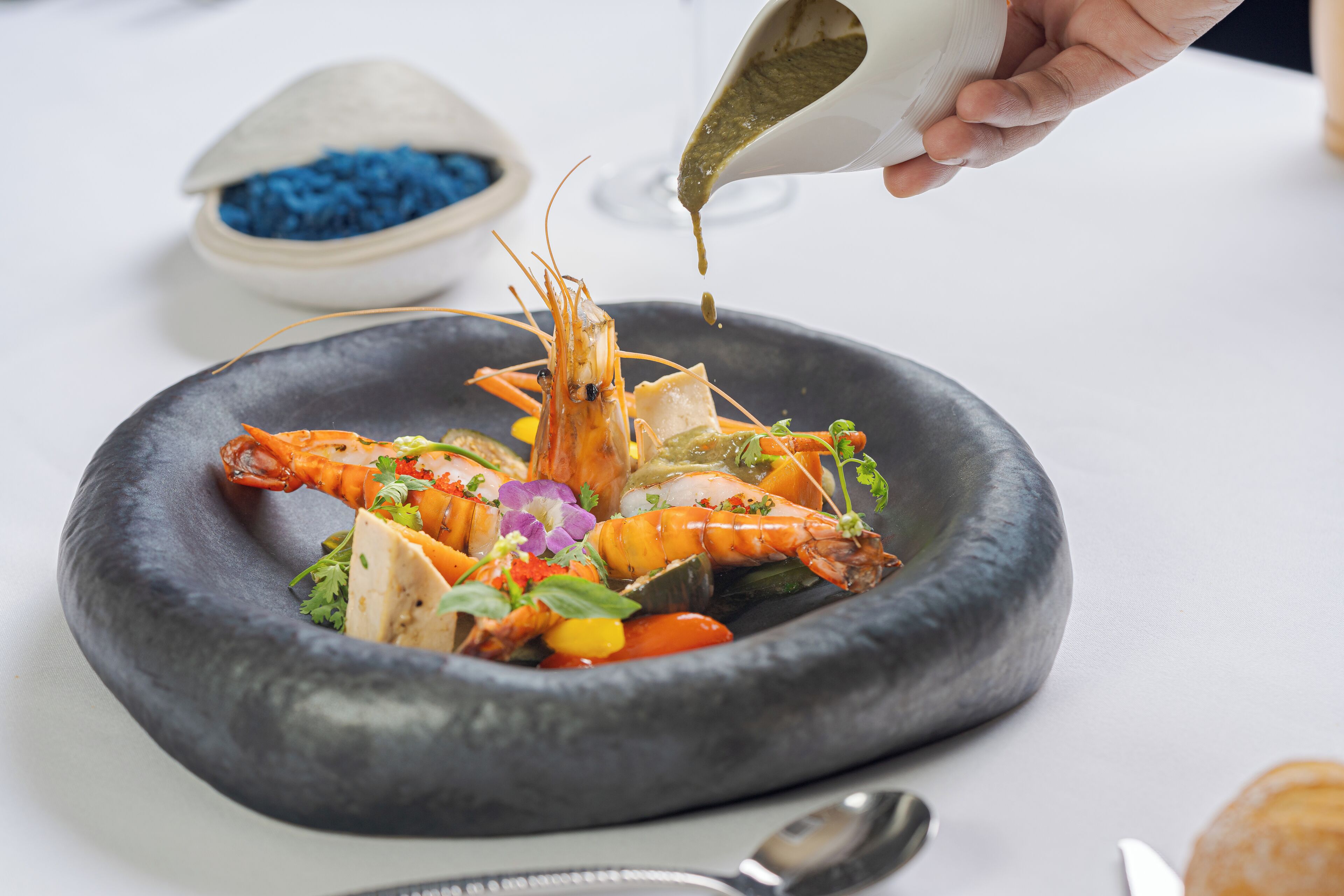 Un plato de mariscos con verduras y hierbas, decorado con salsa verde.