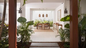 A wooden archway leading to a dining area with a table and chairs, surrounded by lush tropical plants. - Plantation Urban Resort & Spa (Phnom Penh)