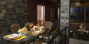 Un coin repas avec un mur en briques, une table dressée pour quatre personnes avec des assiettes, des verres et un ananas.
