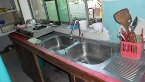 Una cocina con dos fregaderos de acero inoxidable, una estufa y una variedad de utensilios en un organizador.