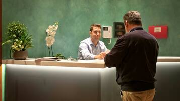 A reception desk with a potted plant and a telephone.