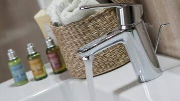 Un lavabo con agua corriente, una rosa y artículos de aseo.