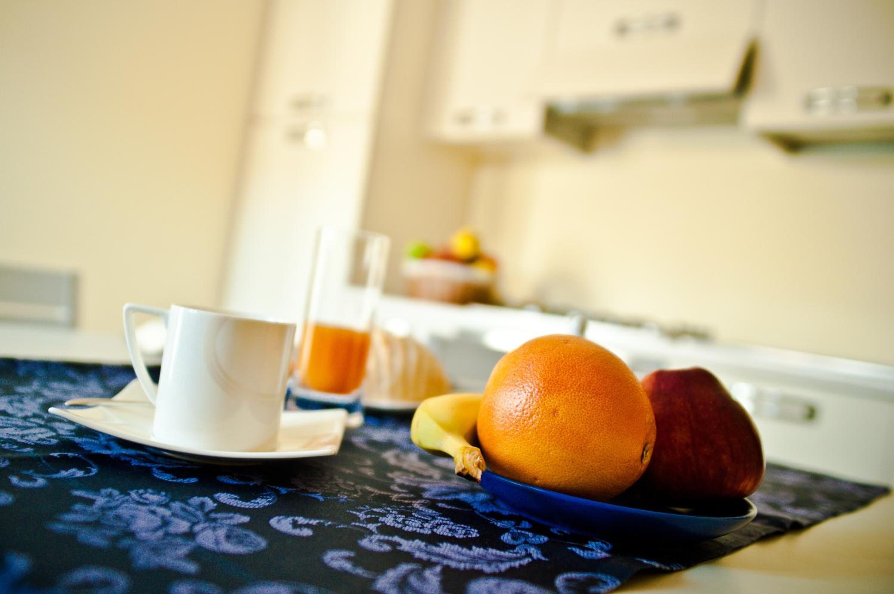 A breakfast setting with a cup, orange, and banana on a table.