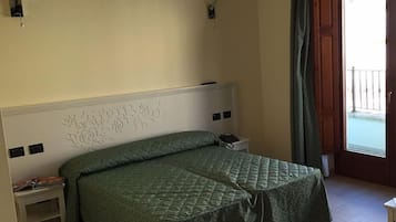 Een slaapkamer met een bed, bedlampen, een nachtkastje en uitzicht op het omliggende landschap.