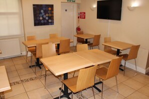 A classroom with wooden tables and chairs, a whiteboard, and a television on the wall. - Belgrave House Hotel (London)