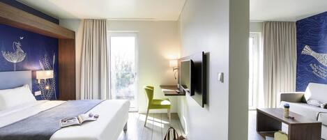A hotel room with a bed, a desk, a TV, a chair, and a sofa.