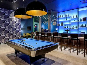 A pool table with a bar area featuring shelves of bottles. - ibis Styles Konstanz (Konstanz)